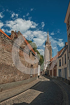 Long brick wall, tower and houses under blue sky on City CenterÃ¢â¬â¢s street of Bruges.